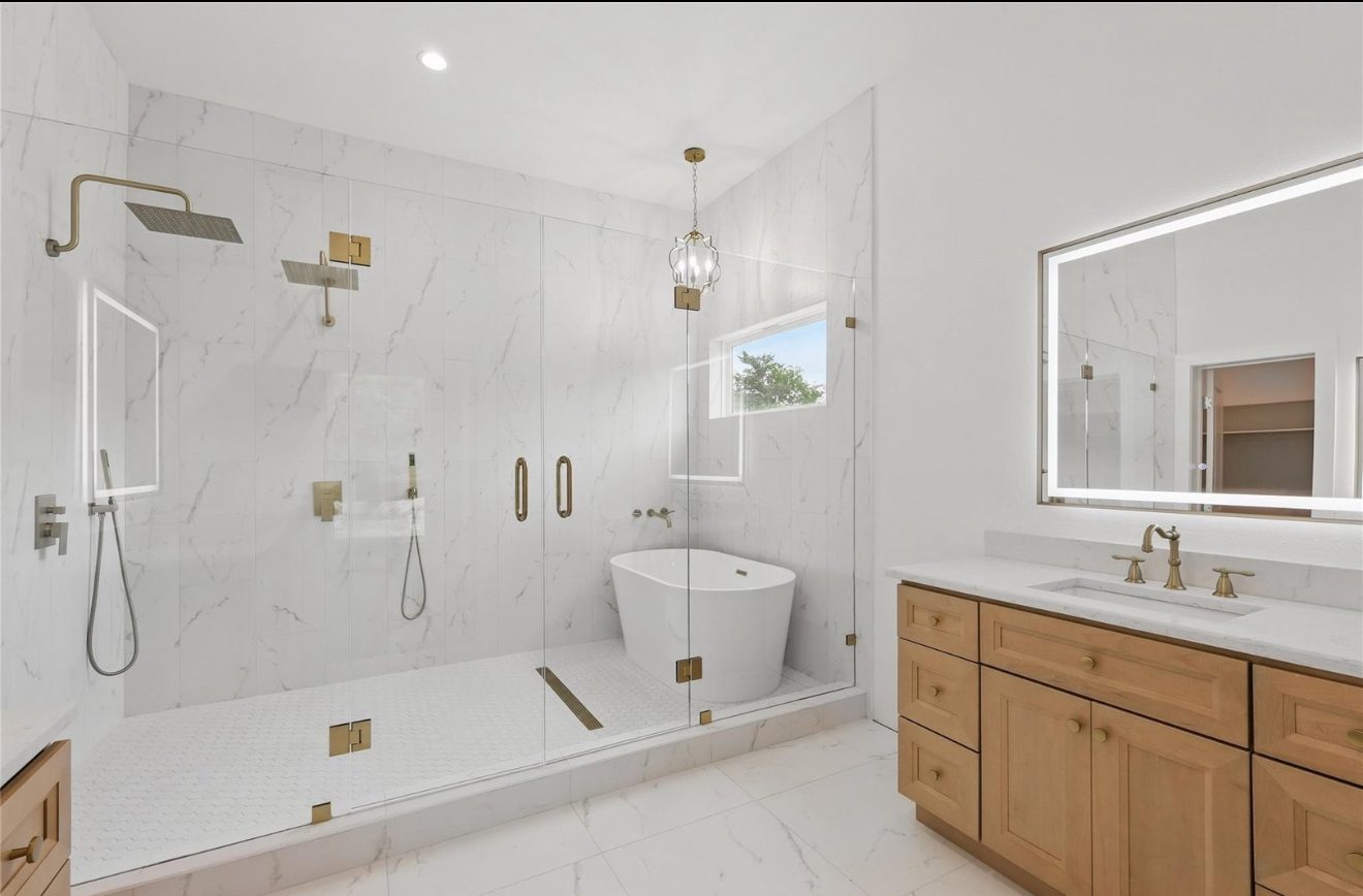 Primary bath with marble wet room, freestanding tub and dual rain heads