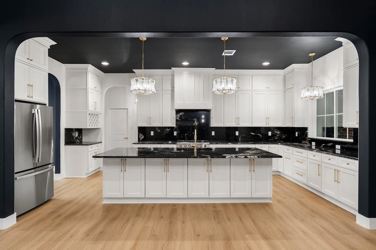 Renovated kitchen with white cabinetry, black granite and gold hardware