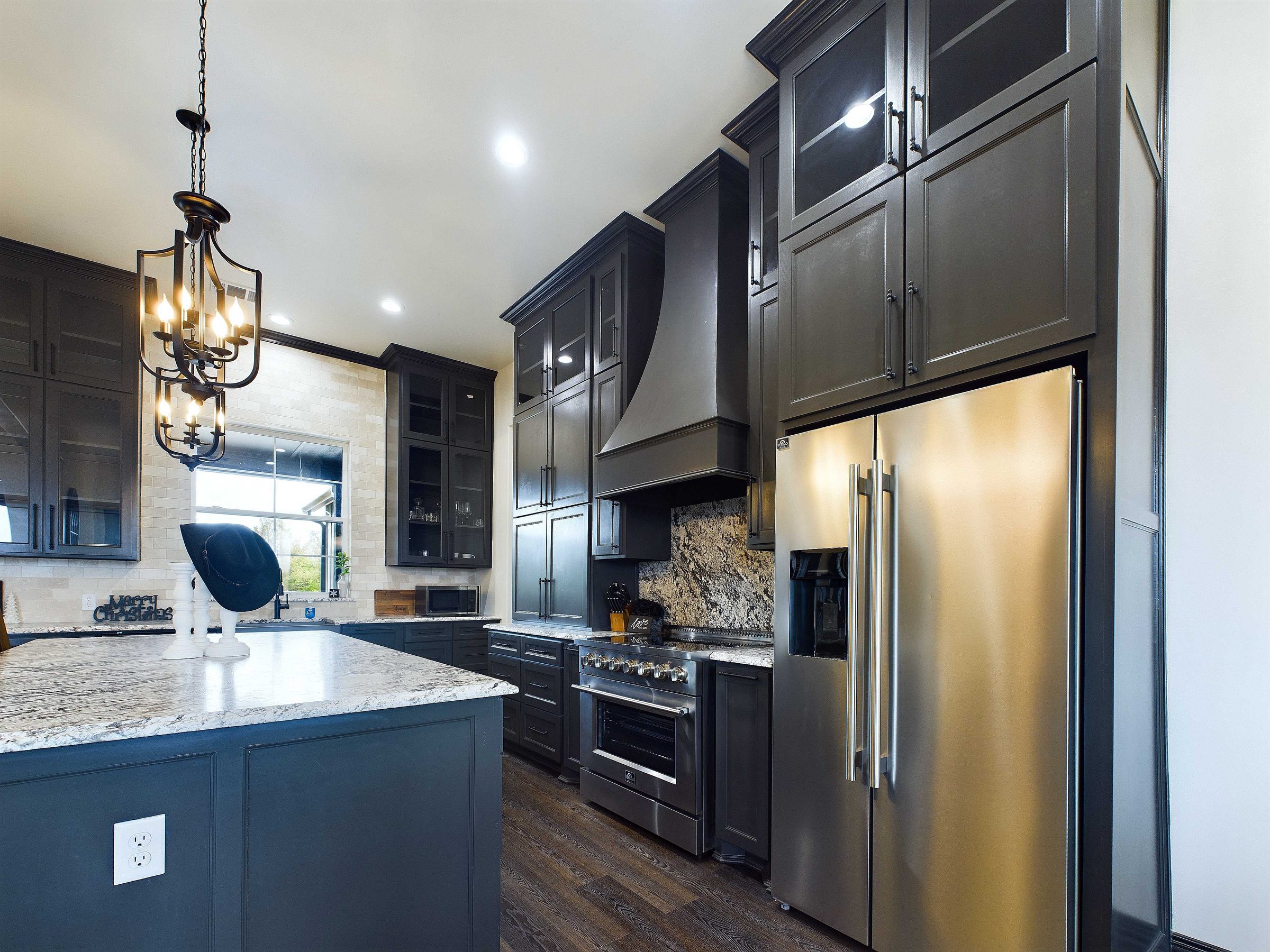Custom kitchen with dark stained cabinetry, granite island and lantern pendants