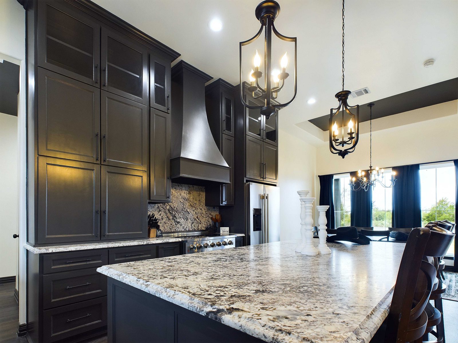 Dark stained cabinetry with granite island and lantern pendants