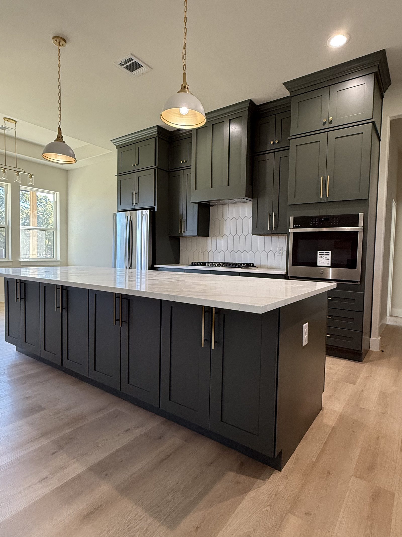 Kitchen with deep green cabinetry and quartz island