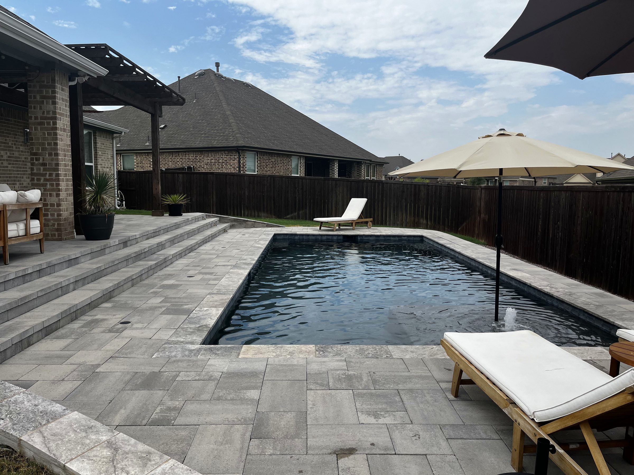 Custom gunite pool with dark plaster, paver deck and cedar pergola