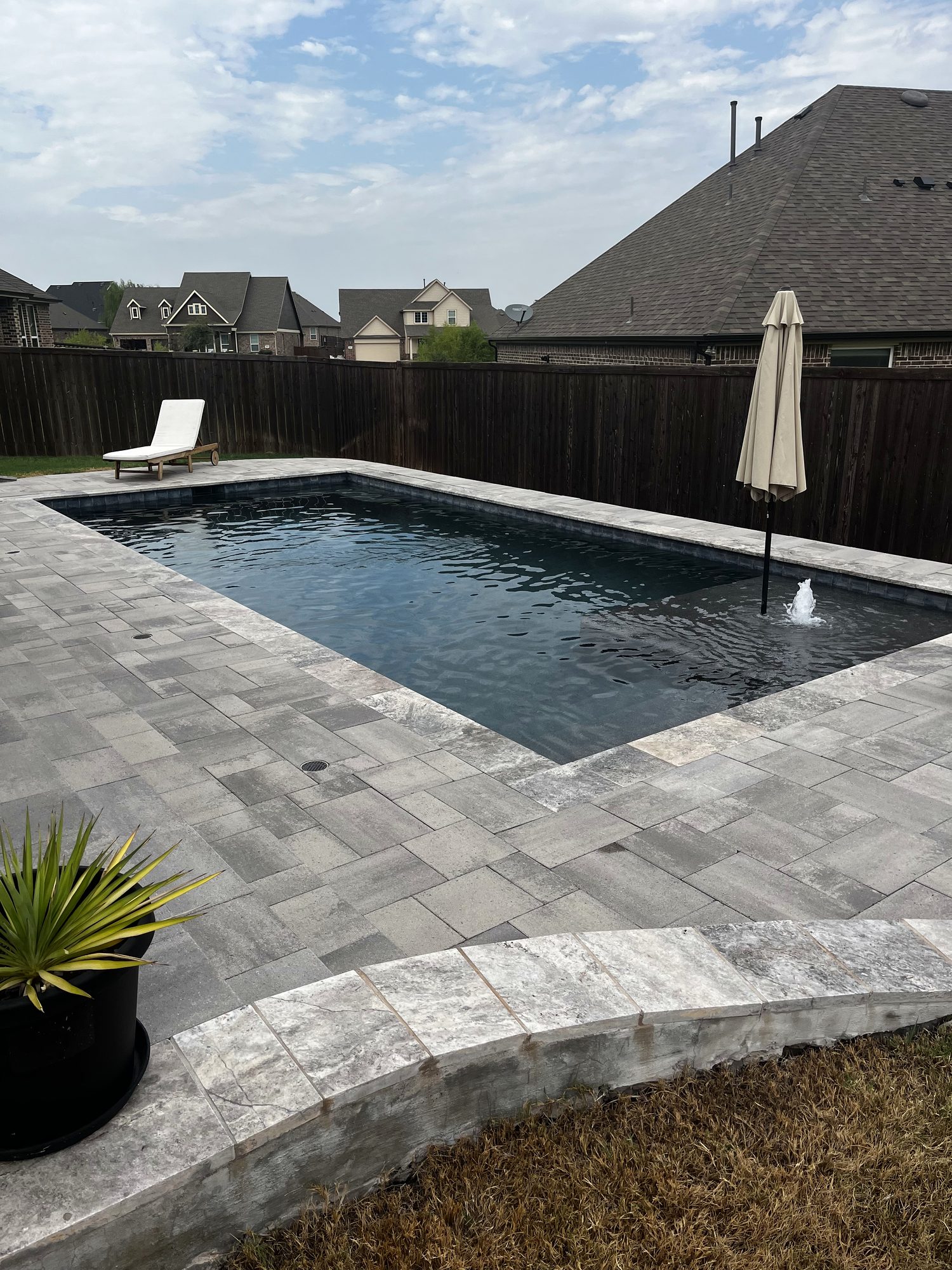 Gunite pool with dark plaster and travertine coping