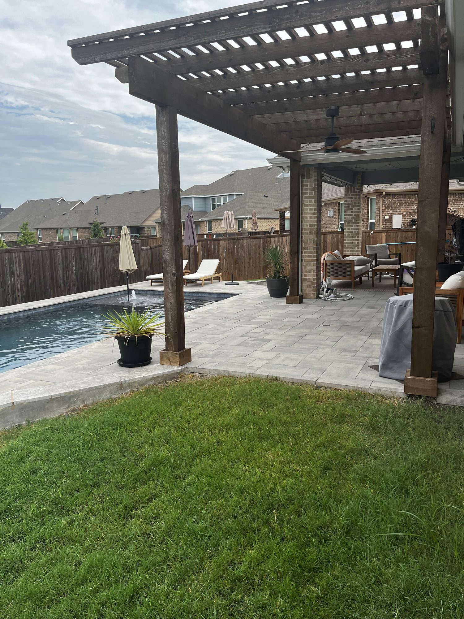 Cedar pergola over a paver patio beside the pool